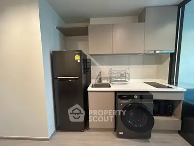 Modern kitchen with sleek appliances including fridge, washing machine, and electric stove in compact layout.
