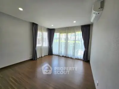 Spacious empty room with large windows and wooden flooring, perfect for customization.