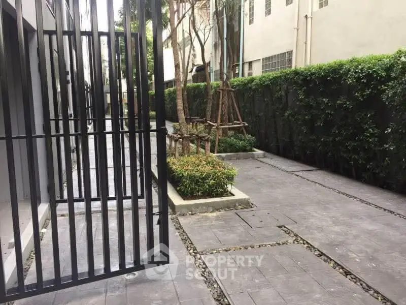 Modern apartment building entrance with lush greenery and sleek design.