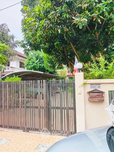 Charming residential property with lush greenery and secure gated entrance, perfect for serene living.