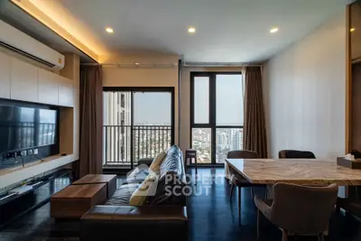 Modern living room with city view, featuring sleek furniture and large windows for natural light.