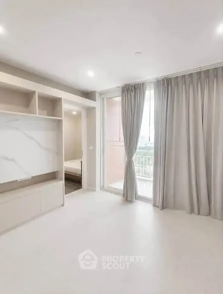 Spacious modern living room with large windows and elegant curtains in a bright apartment.