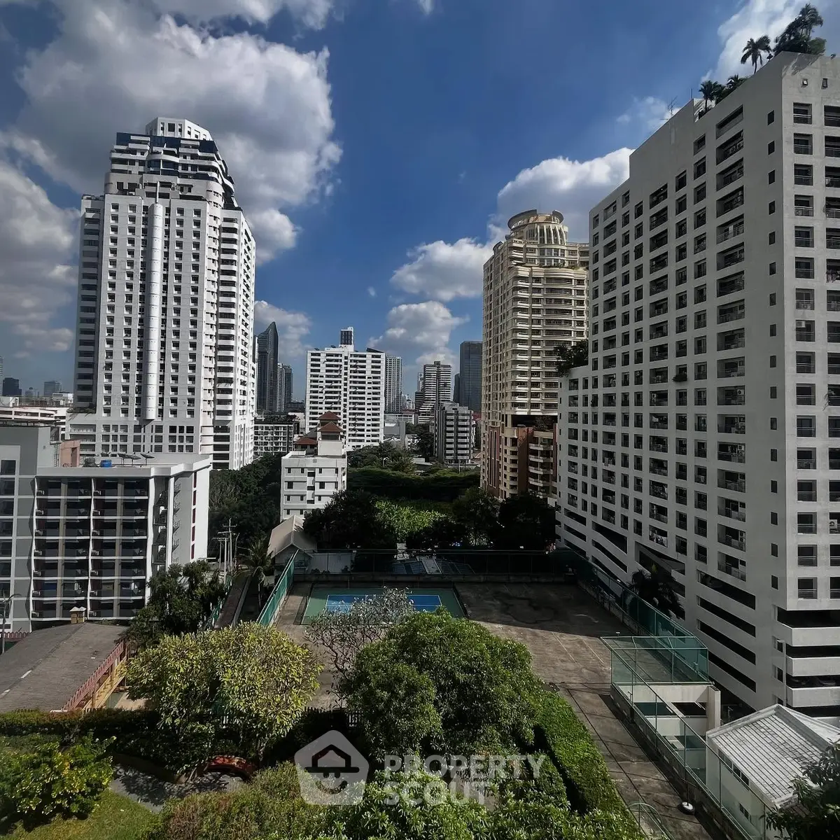 Stunning cityscape view from a high-rise balcony overlooking lush greenery and modern skyscrapers.