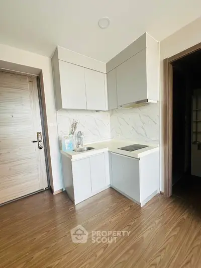 Modern compact kitchen with sleek white cabinets and wood flooring