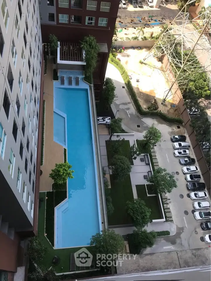 Stunning aerial view of modern apartment complex with large swimming pool and lush greenery.