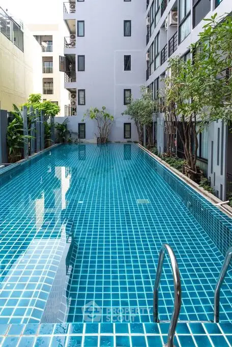 Luxurious residential building with a stunning outdoor pool and lush greenery.