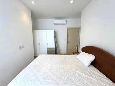 Spacious bedroom with modern furnishings and ample natural light, featuring a comfortable bed and sleek wardrobe.