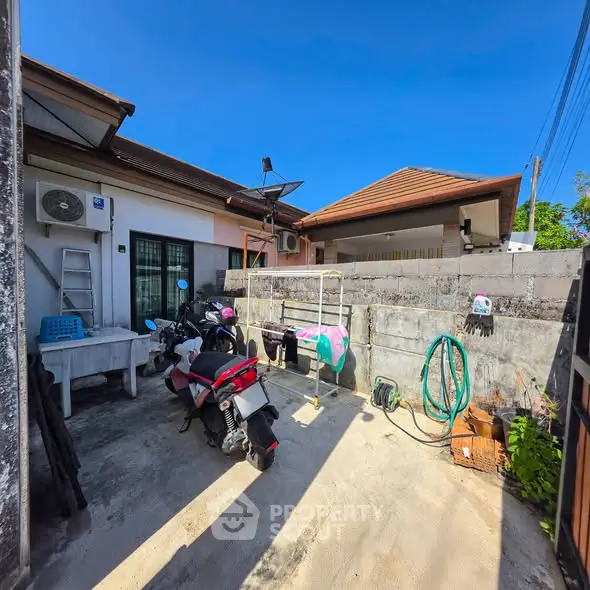 Charming outdoor space with laundry area and motorbike parking in a sunny residential setting.