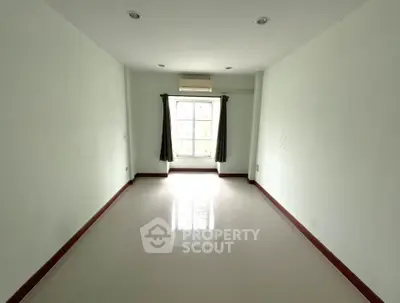 Spacious empty room with large window and air conditioning, ideal for customization.