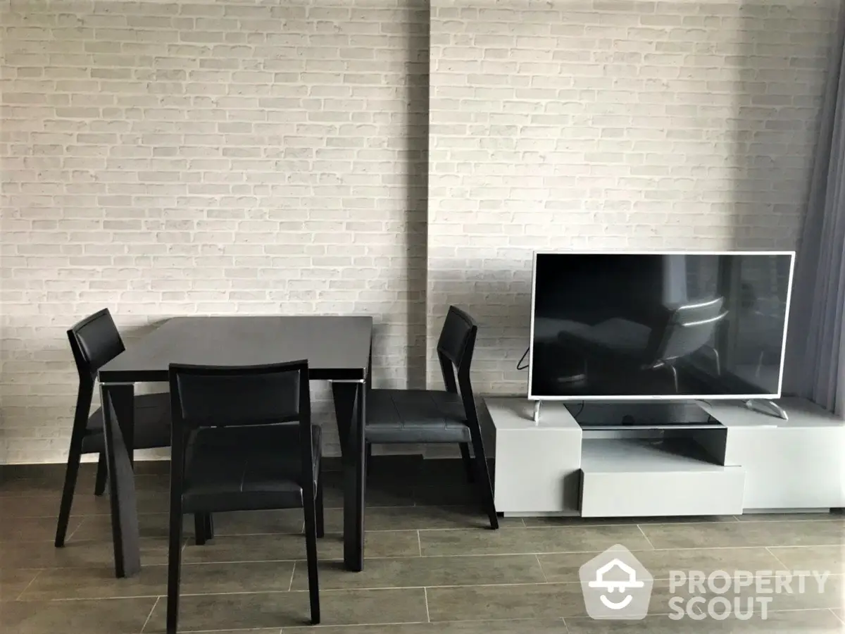 Modern minimalist living room with sleek furniture and large flat-screen TV, featuring a stylish brick wall and elegant floor tiling.