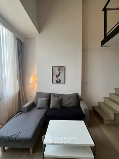 Modern living room with stylish gray sofa and elegant decor in a bright, airy space.