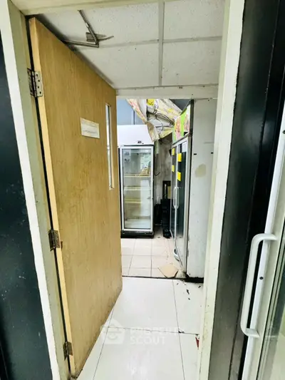 Commercial kitchen storage area with refrigerators and tiled flooring