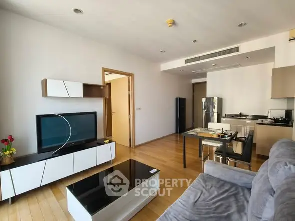 Modern living room with open kitchen, sleek furniture, and wooden flooring