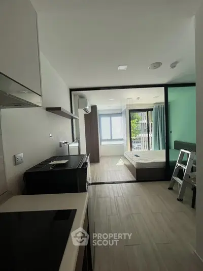 Modern studio apartment with open layout and large windows for natural light.