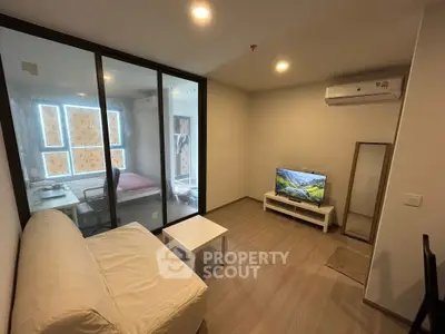 Modern living room with glass partition, cozy sofa, and wall-mounted TV in a stylish apartment.