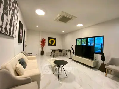 Modern living room with stylish decor, large TV, and elegant furniture in a bright, spacious setting.