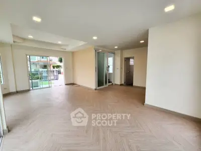 Spacious modern living room with elegant flooring and ample natural light, perfect for family gatherings.