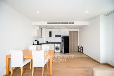 Modern open-plan kitchen and dining area with sleek appliances and wooden flooring.
