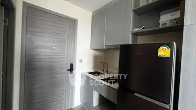 Modern kitchen with sleek cabinetry and stainless steel fridge in compact layout.
