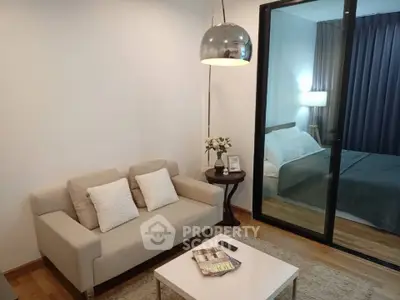Modern living room with cozy sofa and view into elegant bedroom