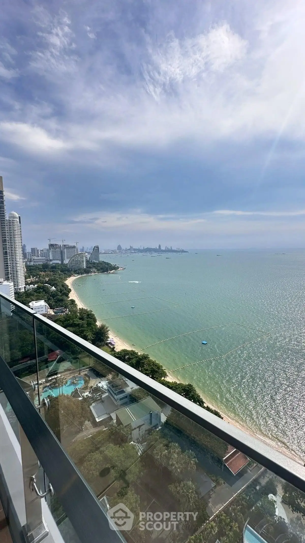 Stunning beachfront view from high-rise balcony overlooking ocean and city skyline.