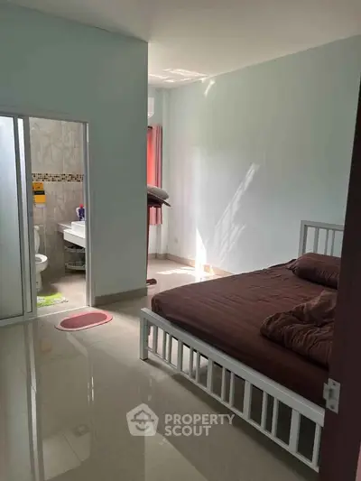 Cozy bedroom with attached bathroom, featuring natural light and modern furnishings.