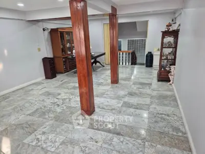 Spacious interior with marble flooring and wooden columns, ideal for versatile living space.