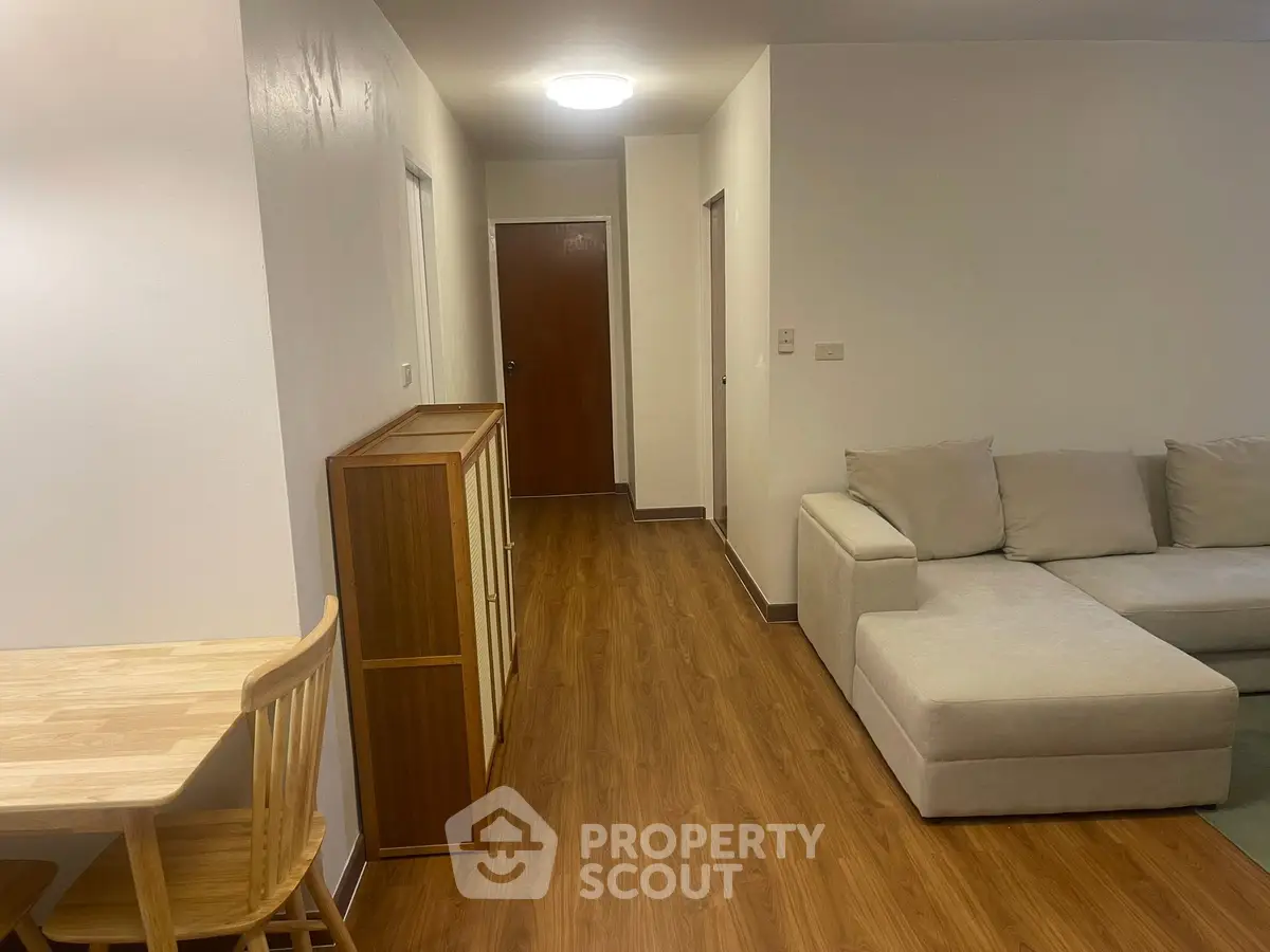 Spacious living room with modern furniture and wooden flooring in a cozy apartment.