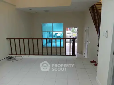 Spacious two-level interior with tiled flooring and wooden railing, ideal for modern living.