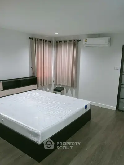 Modern bedroom with minimalist design featuring a large bed and air conditioning.