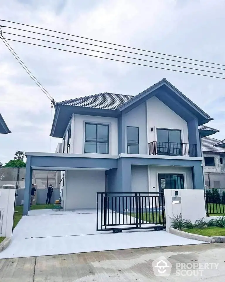 Modern two-story house with sleek design and spacious driveway in suburban neighborhood.