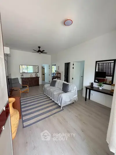 Spacious living room with modern decor and ample natural light, featuring a cozy sofa and stylish furnishings.