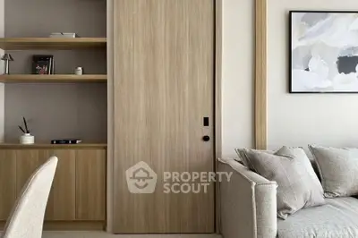 Modern living room with neutral tones, featuring a sliding wooden door and elegant shelving.