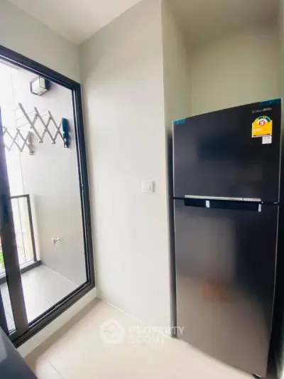 Modern kitchen corner with sleek black fridge and balcony access