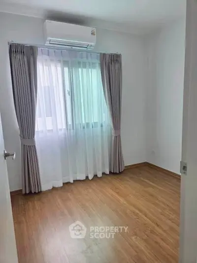 Bright and airy bedroom with wooden flooring and large window, perfect for natural light.