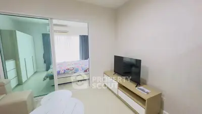 Modern living room with TV and view into cozy bedroom through glass doors.