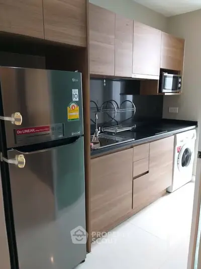Modern kitchen with sleek appliances and wooden cabinetry in a compact layout.
