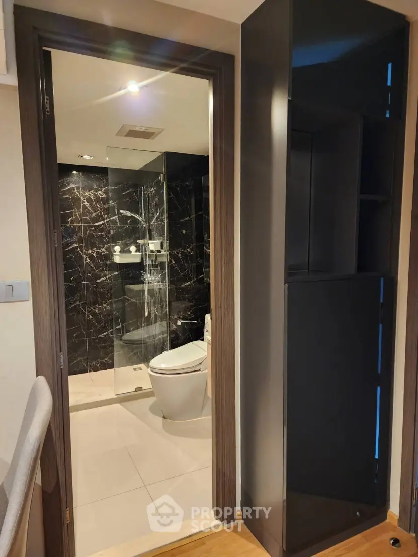 Modern bathroom with sleek black marble tiles and glass shower enclosure