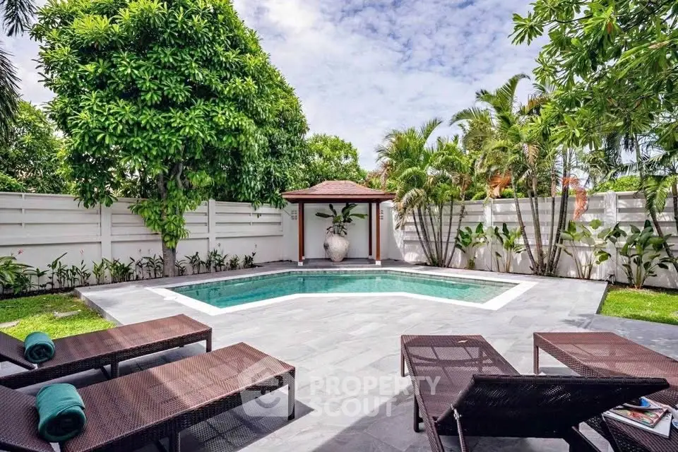 Luxurious private pool area with lush greenery and stylish sun loungers, perfect for relaxation and entertainment.