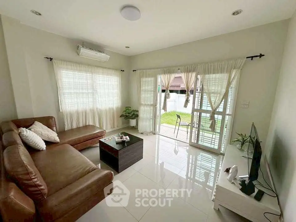 Spacious living room with leather sofa and garden view, perfect for relaxation.