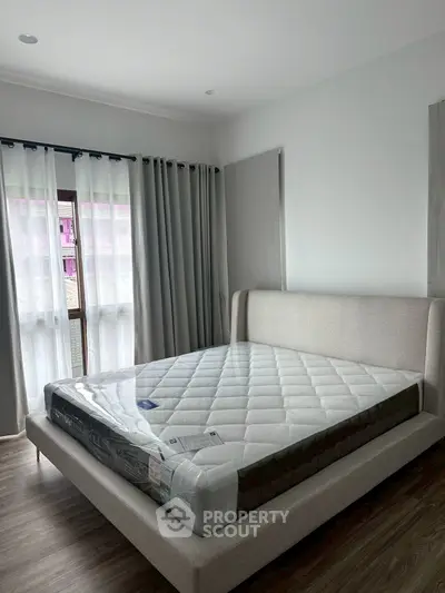 Spacious bedroom with elegant bed and natural light from large windows.