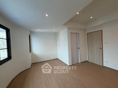 Spacious empty room with wooden flooring and modern lighting, ideal for customization.