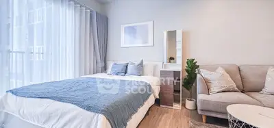 Modern bedroom with cozy bed, stylish decor, and natural light from large windows.