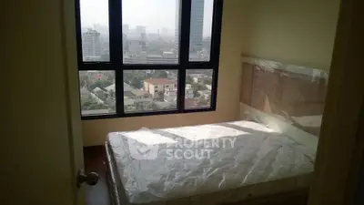 Spacious bedroom with large windows offering stunning city views in a modern apartment.