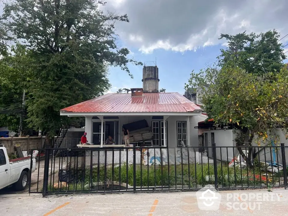 Charming single-story house with red metal roof and spacious front yard