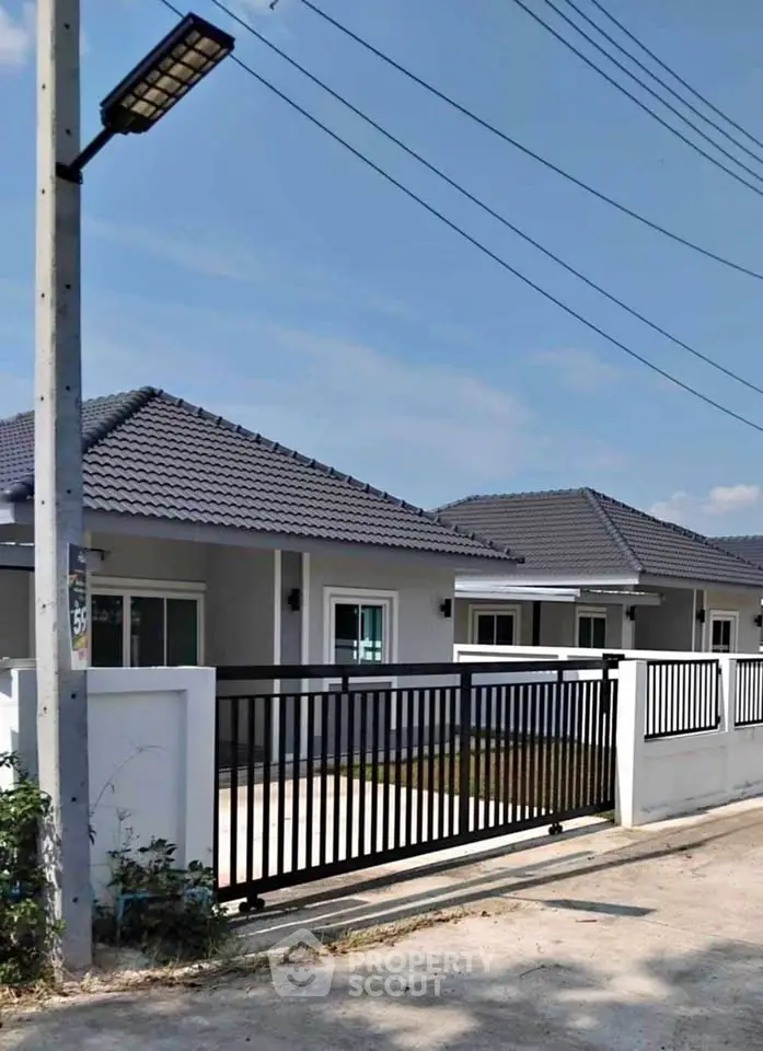 Modern single-story house with sleek black gate and tiled roof in a suburban setting.