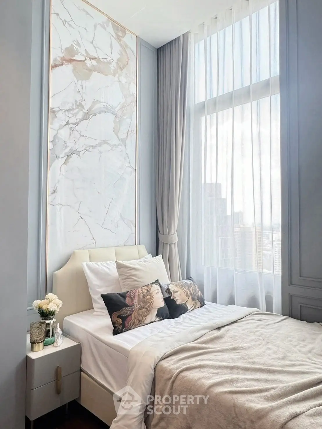 Luxurious bedroom with elegant marble accent wall and large window offering city views.