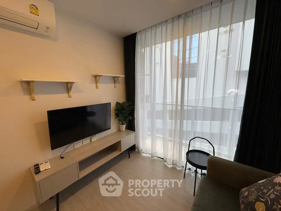 Modern living room with sleek TV stand, air conditioning, and large window with sheer curtains.