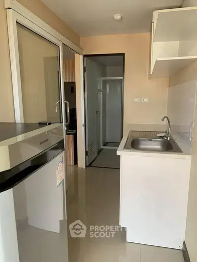 Compact kitchen with modern appliances and sleek design in a cozy apartment setting.