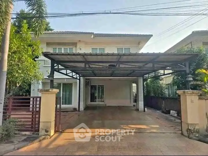 Spacious two-story house with covered carport and lush greenery, perfect for family living.